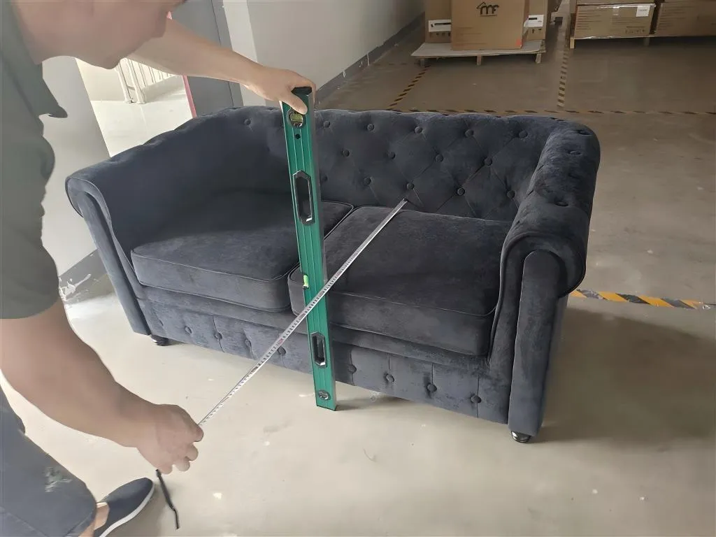 Inspector measuring a tufted velvet sofa with a level and tape