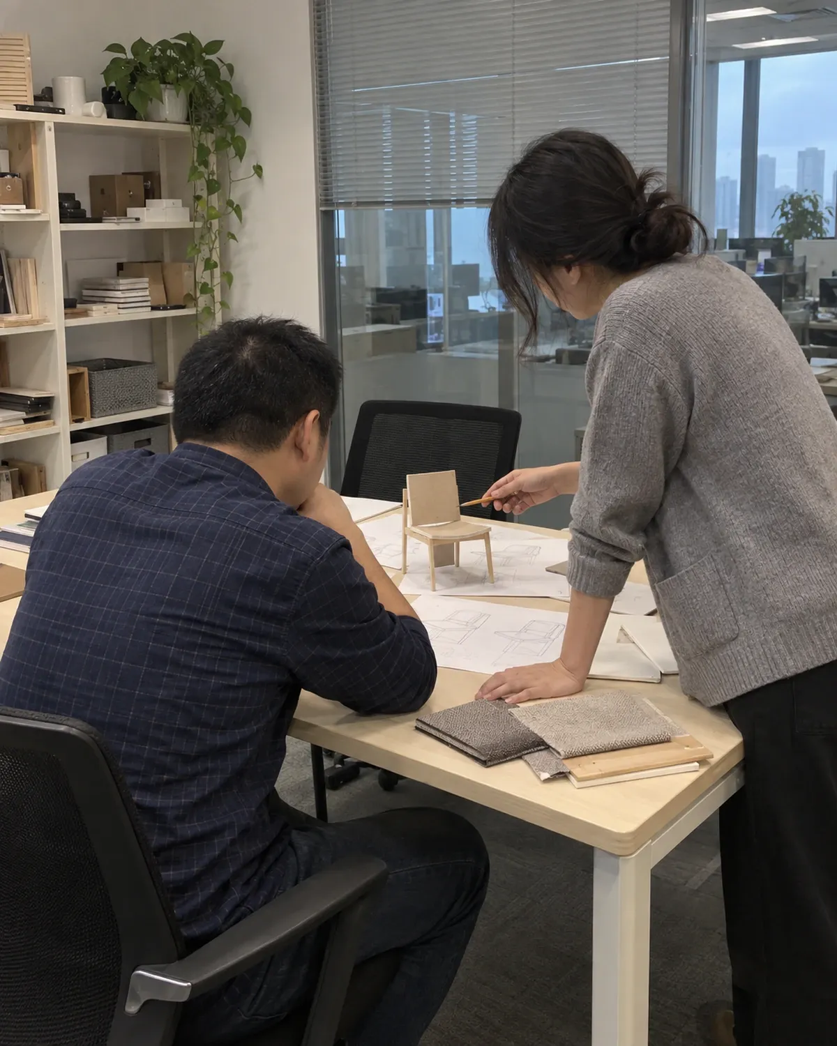 Two colleagues reviewing furniture sketches and a chair model